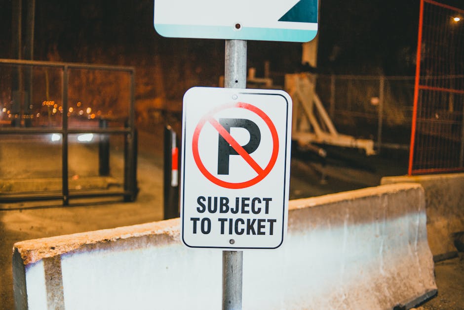 A green and white parking restriction sign mounted on a metal post outdoors against a blue sky with some clouds and blurred green foliage in the background. The sign indicates a two-hour parking limit from 8 am to 8 pm, except on Sundays, with the text '2 HOUR PARKING 8AM TO 8PM EXCEPT SUNDAY' clearly visible. The sign is positioned on a paved surface, and its purpose is to communicate parking rules in Lamorbey, which is relevant for home relocations or moving logistics in the area, as managed by Man with Van Lamorbey. The image captures the sign's details accurately, highlighting its role in local parking regulations that may impact furniture transport and house moving activities.